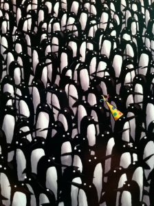 Penguin in a party hat standing out from the crowd.